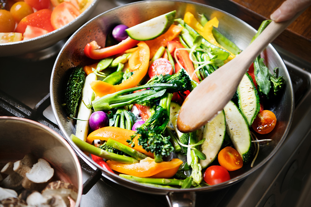 A colorful assortment of vegetables sizzling in a pan on a stove, creating a delicious and healthy meal.