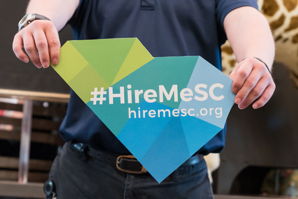 man holds Hire Me SC sign
