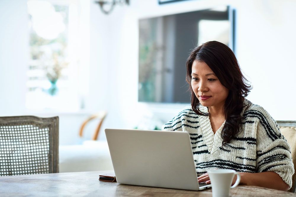 woman sitting at table with laptop and mug