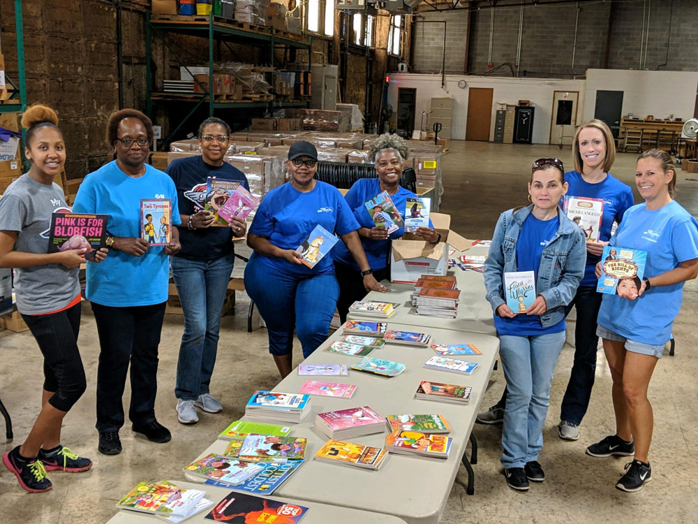 group of women volunteers hold books at donation site