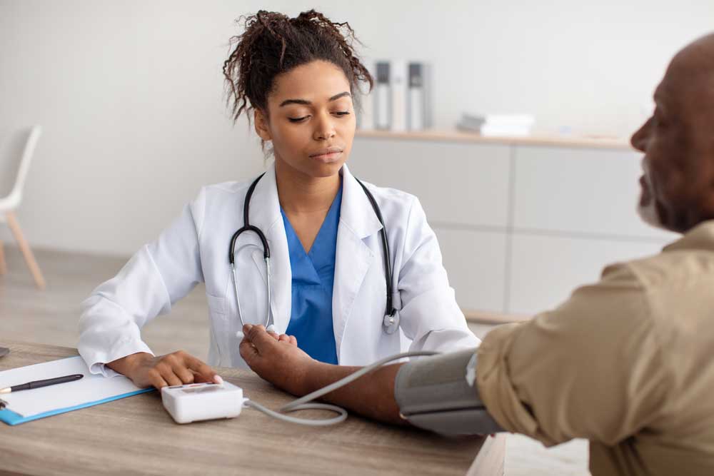 woman in white coat with blood pressure cuff on man arm