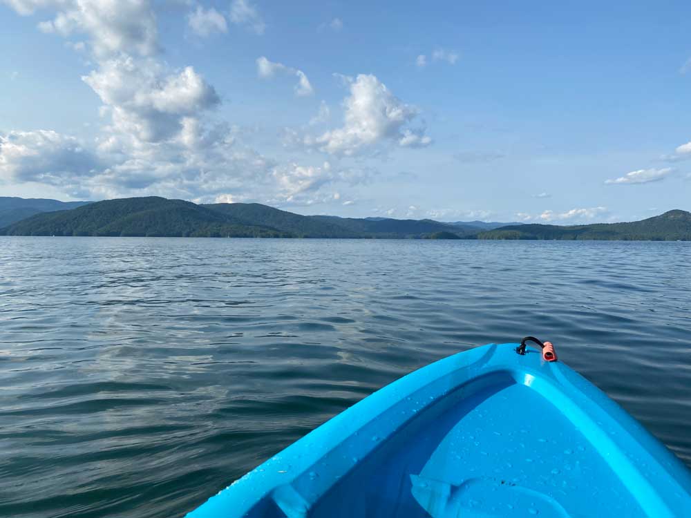 tip of kayak on water with mountains in distance